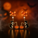 Halloween-themed earrings with black cats, pumpkins, and orange bows on a dark background - Parker and Stone