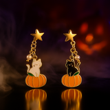 Halloween-themed earrings with cats on pumpkins against a dark background
