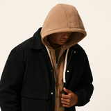 Men’s black corduroy shacket with oversized front pockets and hood, a durable outerwear piece with a sleek rugged edge.