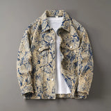 Men’s floral-patterned textured denim-look trucker jacket in beige and navy tones, featuring buttoned chest pockets, long sleeves, and a white shirt layered underneath, displayed flat on a gray background.