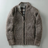 Brown knitted zip-up cardigan laid flat on grey surface, featuring ribbed cuffs, black zip lining, and light grey inner collar detail - luxury textured knitwear for men.